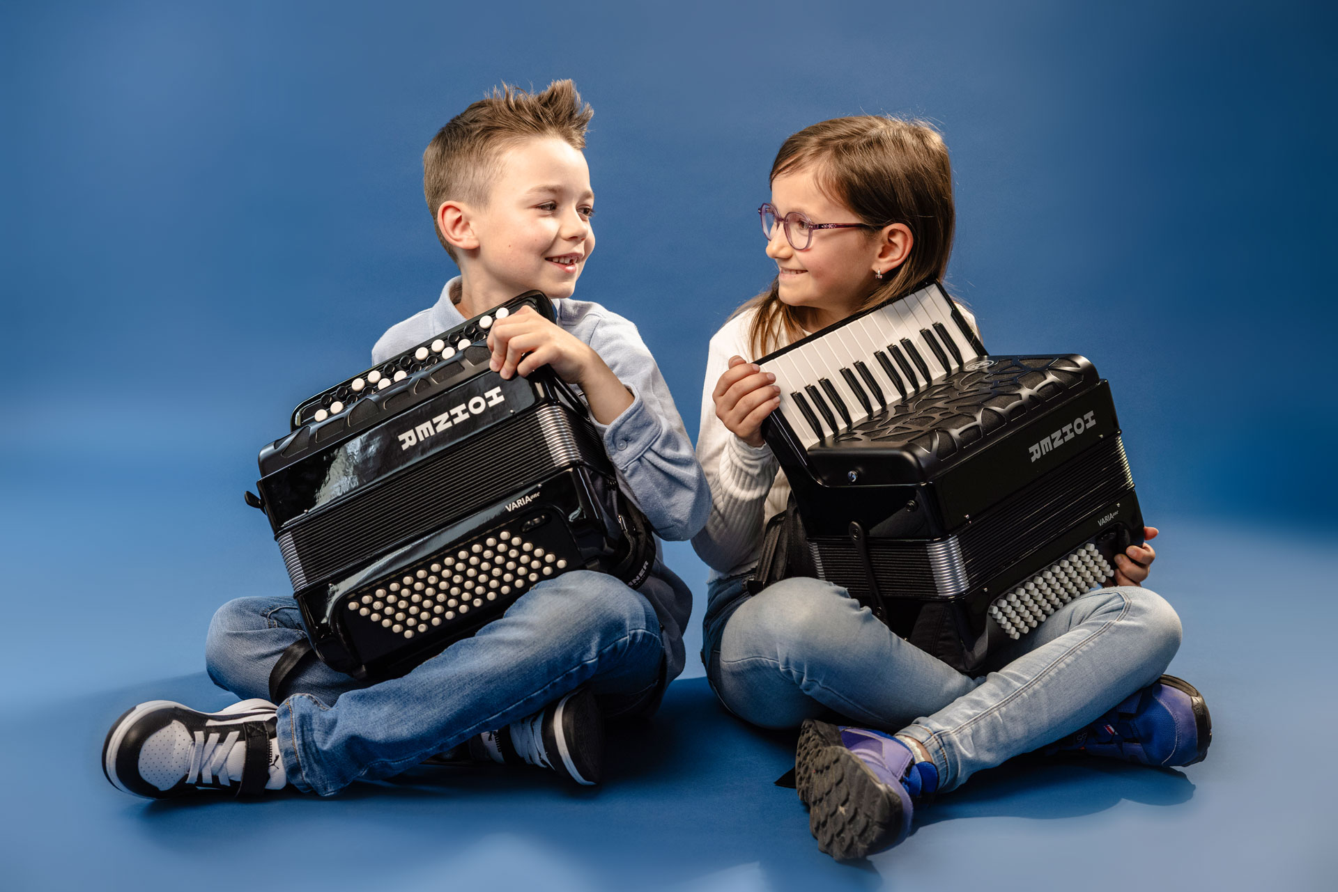 young girl  and boy, brown hair, sitting with two HOHNER accordions in their hands
