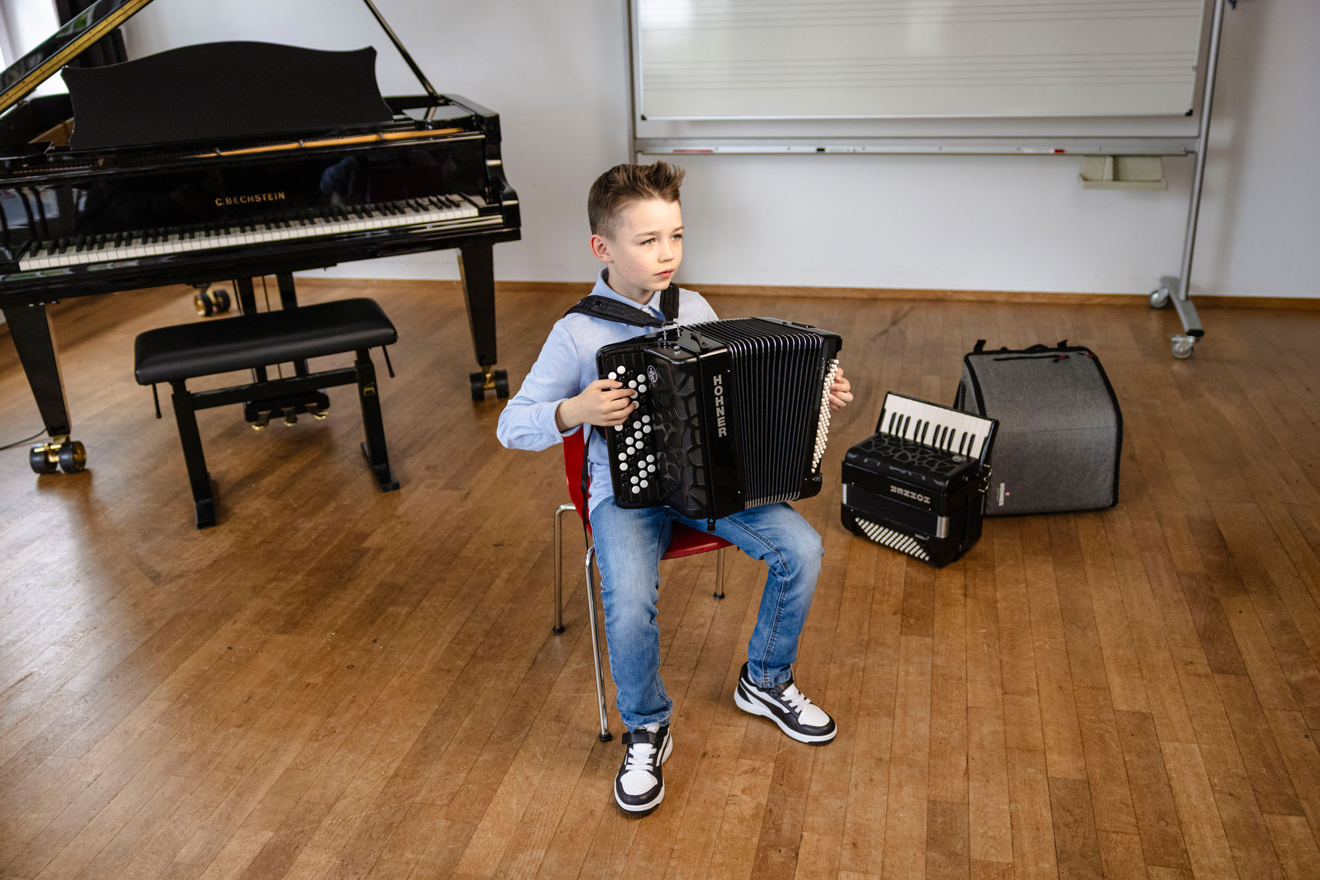 young boy, brown hair, playing HOHNER accordion