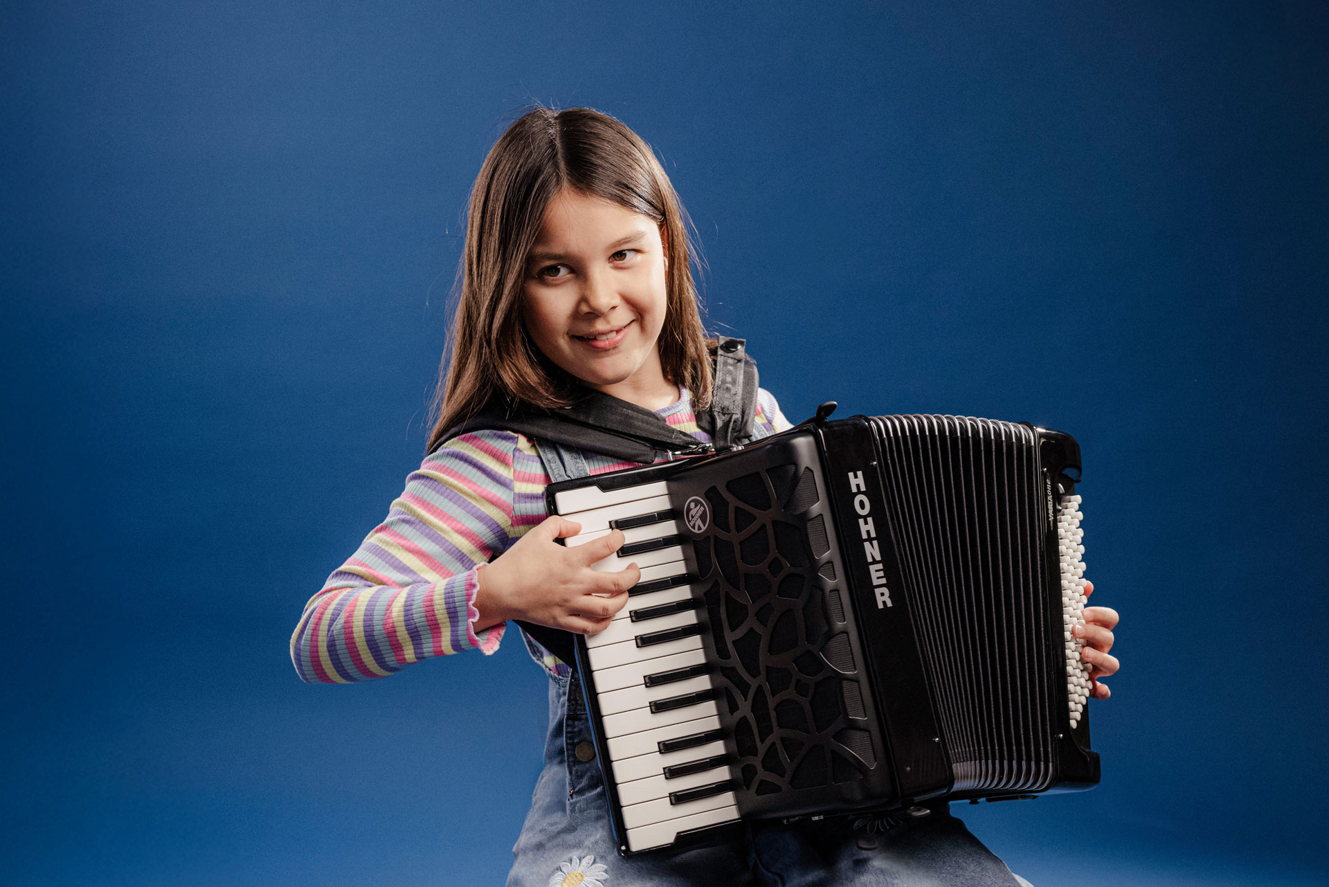 young girl, dark hair, palying HOHNER accordion