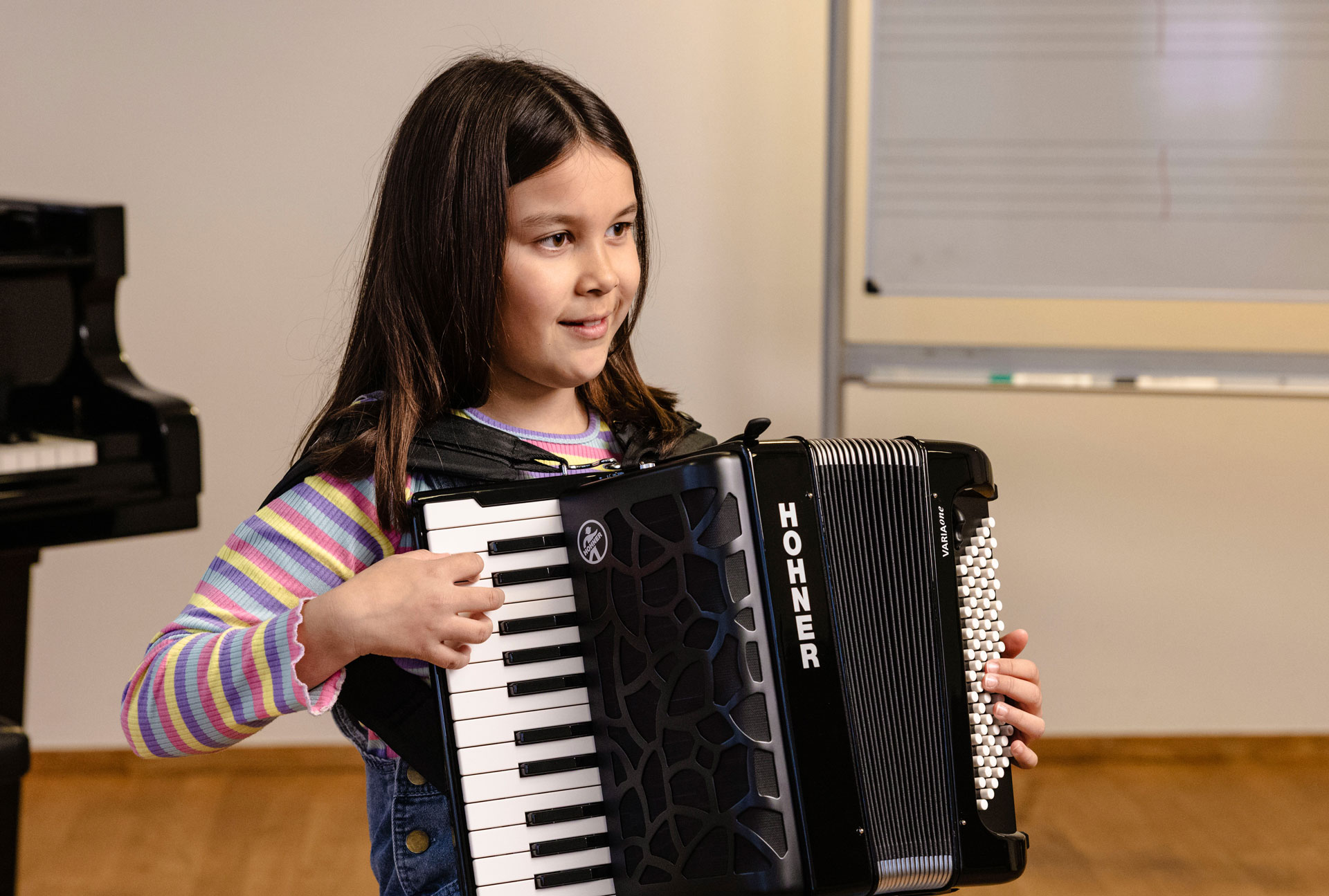 young girl, dark hair, palying HOHNER accordion
